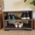 Un banc en bois avec deux étagères contenant des chaussures placées dans une entrée de maison, offrant à la fois un siège et un rangement pratique pour les chaussures.