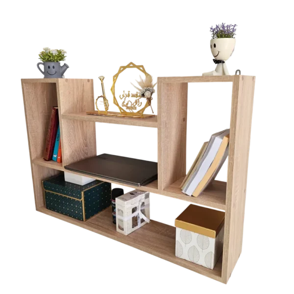 Étagère murale asymétrique de couleur bois clair, vue de trois quarts, garnie de livres, d'un ordinateur portable, de boîtes et d'objets décoratifs, sur fond transparent.