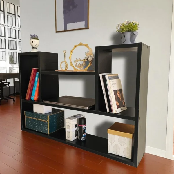 Étagère murale noire posée sur un parquet en bois rougeâtre, dans un bureau ou salon décoré.