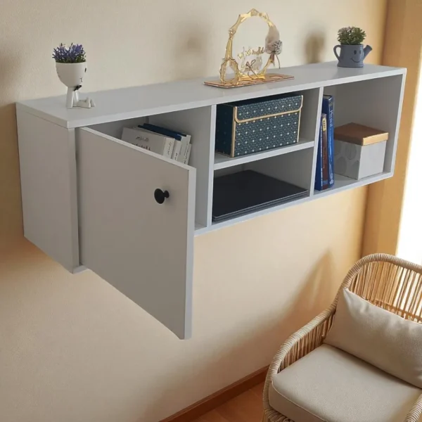 Une étagère murale blanche flottante avec une porte de placard ouverte, des livres et des objets décoratifs.