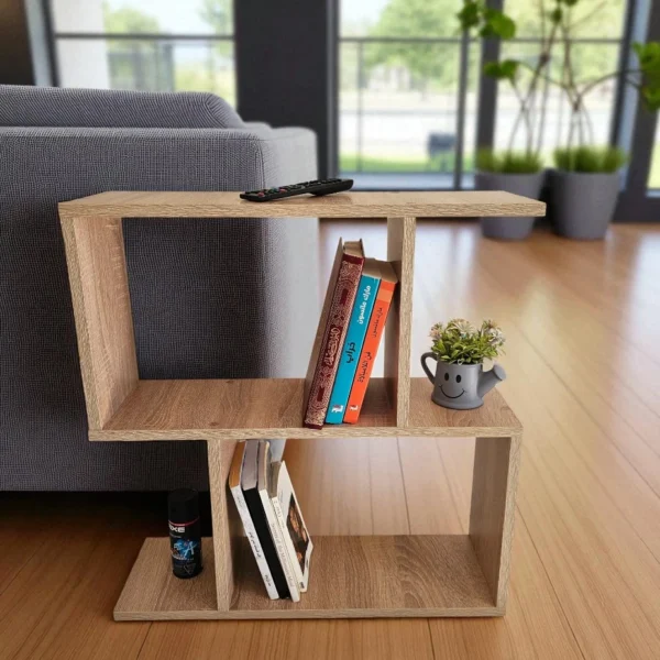 Petite table d'appoint polyvalente en bois clair à côté d'un canapé gris, idéale comme bout de canapé ou table de chevet, offrant des espaces de rangement pour livres et télécommande.