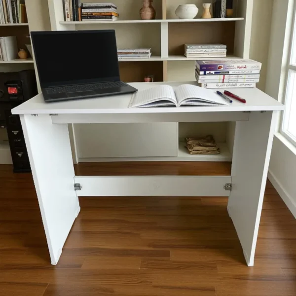 Un bureau démontable blanc, avec un ordinateur et des livres, devant une grande bibliothèque.