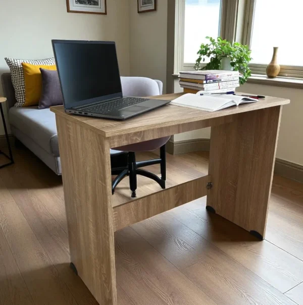 Un bureau démontable en bois, installé dans un salon près d'une fenêtre, avec un canapé en arrière-plan.