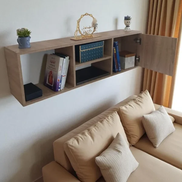 Bibliothèque suspendue au mur, avec la porte du placard ouverte, au-dessus d'un canapé beige dans un salon.