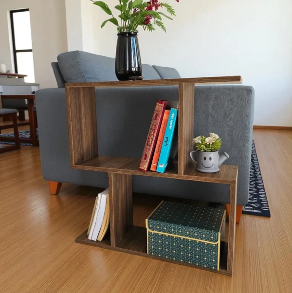 Petite table de salon en bois foncé de style géométrique, utilisée comme table étagère à côté d'un canapé gris avec des livres et un vase.