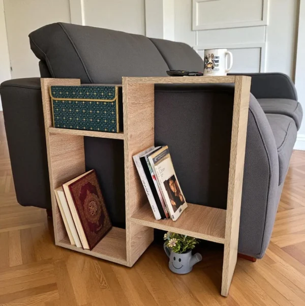 Table d'appoint en bois avec compartiments de rangement, utilisée comme bout de canapé, affichant des livres, une boîte décorative et une petite plante.