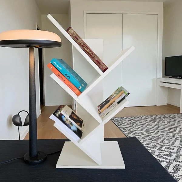 Bibliothèque moderne blanche posée sur un bureau noir dans un salon, servant de rangement pour des livres.