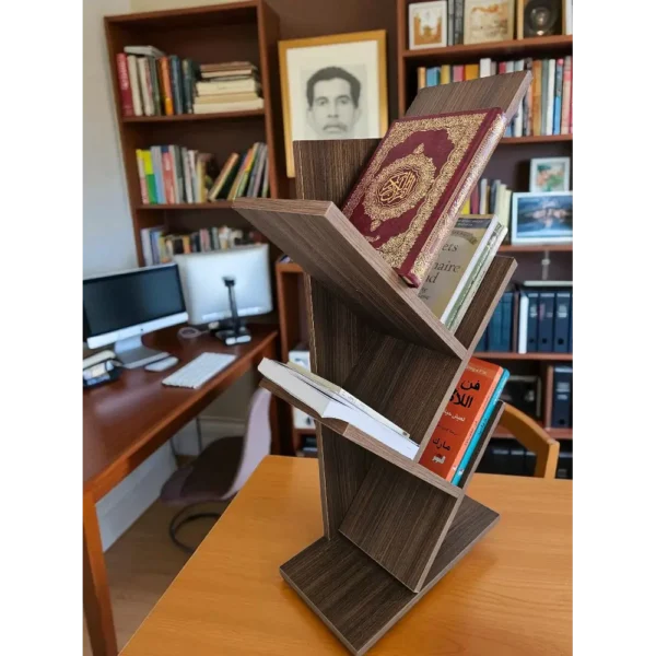 Petite bibliothèque de salon en bois foncé, posée sur une table dans un bureau avec des livres en arrière-plan.