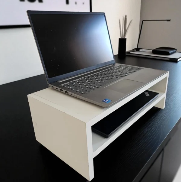 Rehausseur de moniteur blanc utilisé comme accessoire de bureau ergonomique sur une table noire.