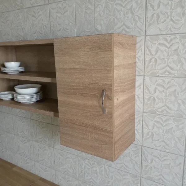 Meuble haut suspendu finition bois fermé situé à côté d'étagères avec assiettes et bols.