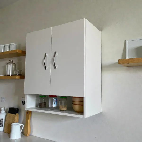 Placard mural blanc mat gain de place, installé dans une cuisine moderne pour le rangement d'articles de nettoyage ou de vaisselle.