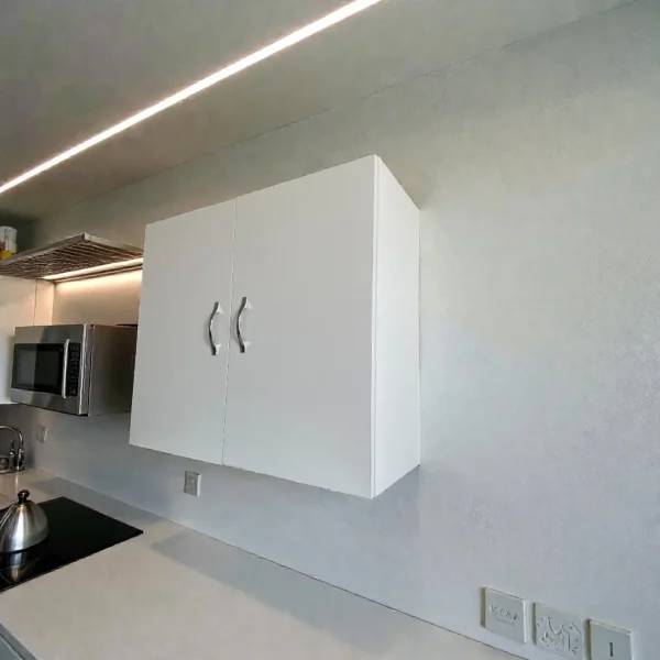 Meuble haut de cuisine blanc mat suspendu au-dessus d'un plan de travail, design moderne et compact.